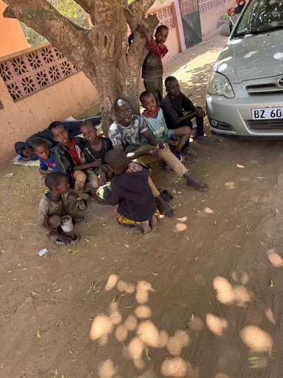 Children outside sitting by a car