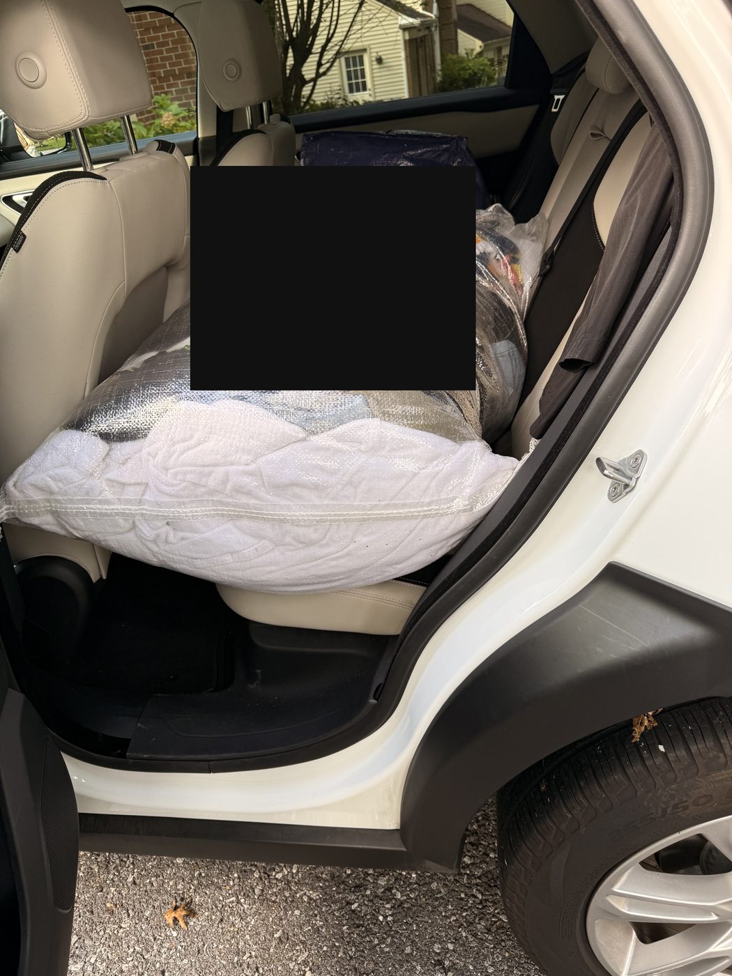 Wrapped bags of donated clothing and essentials packed across the back seat of an SUV in Maryland.
